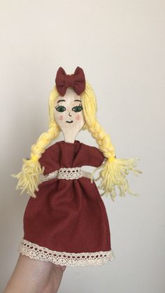 a hand holding a doll wearing a red dress