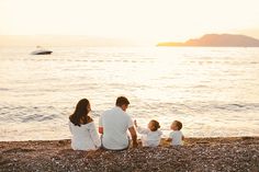 a family sitting on the beach at sunset