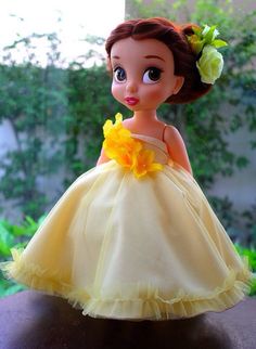 the doll is wearing a yellow dress with flowers in her hair