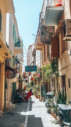 an alleyway with many potted plants and parked motorcycles