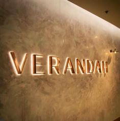 the name verandah is illuminated on a wall in front of a large painting