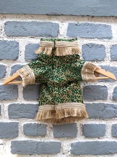 a green and gold dress hanging on a brick wall