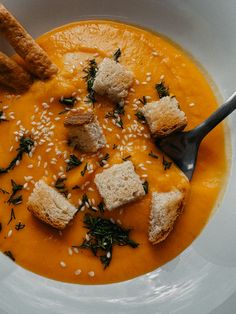 a white bowl filled with soup and croutons