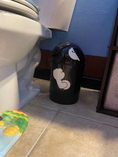 a white toilet sitting next to a black trash can