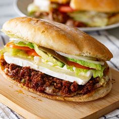 a sandwich with meat and lettuce on a cutting board