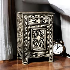 an ornate black and white cabinet next to a clock