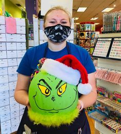 a woman wearing a santa hat and holding a grin face bag in a store aisle