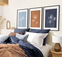 a bed with blue and white sheets in a bedroom next to two pictures on the wall