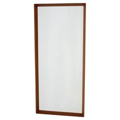 a wooden framed mirror on a white wall with clippings to the bottom edge