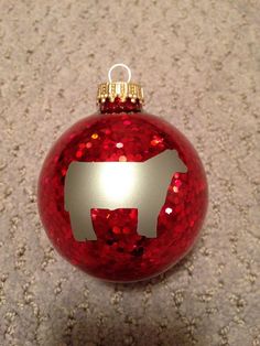 a red ornament with a silver cow on it's side sitting on the ground