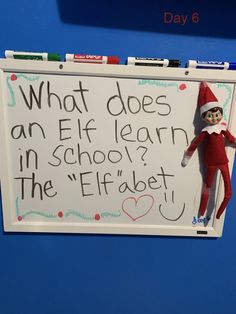 an elf is hanging on the back of a whiteboard with words written in it