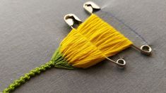 a piece of yellow yarn with green thread on it sitting on top of a gray surface