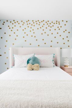 a white bed sitting next to a blue wall with gold polka dots on the walls