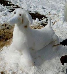 a white dog statue sitting on top of snow next to a person holding an umbrella