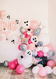 a bunch of balloons that are sitting on the floor in front of a white wall