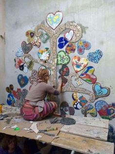 a woman sitting on top of a wooden table next to a wall covered in hearts