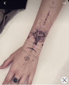 a woman's hand with a tree tattoo on the left wrist and an arrow in the middle