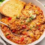 a white bowl filled with food next to bread