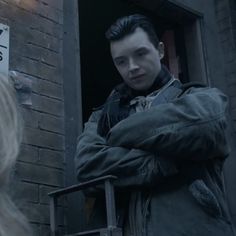 a man standing next to a woman in front of a brick building