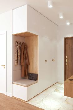 an open closet with coat racks and coats hanging on the wall next to a bench