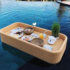 a wicker tray with food on it floating in the water next to a swimming pool