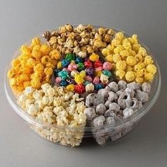 a plastic container filled with lots of different flavored popcorns on top of a table