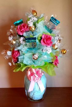 a vase filled with candy and flowers on top of a wooden table next to a wall