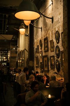 people sitting at tables in a dimly lit restaurant with pictures on the wall behind them