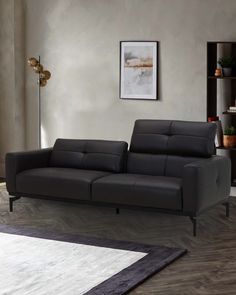 a black leather couch sitting on top of a wooden floor next to a white rug