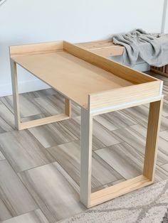 a wooden table sitting on top of a hard wood floor next to a white wall