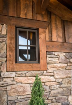 a window on the side of a stone building with a potted plant next to it