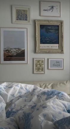 a bed with white sheets and pictures on the wall above it, in front of a window