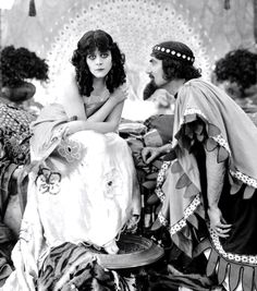 three women sitting on top of a pile of cloth covered furniture in an old fashion photo