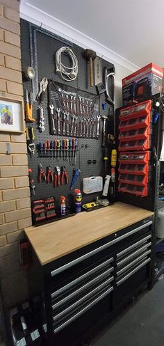 a workbench with lots of tools hanging on the wall next to it's drawers