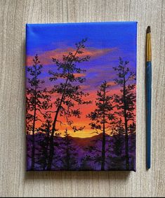 a painting of trees with the sun setting in the background and a pencil resting next to it