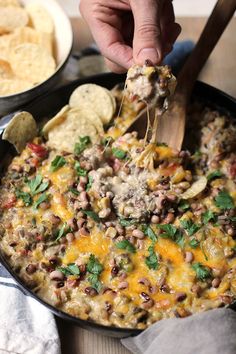 a person scooping some food out of a skillet with tortilla chips