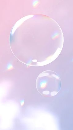 two soap bubbles floating in the air on a pink and blue sky background with white clouds