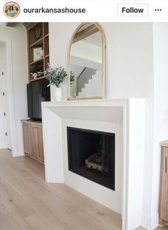 a white fireplace with a mirror above it