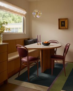 a dining room table with chairs and a bowl of fruit on top of the table