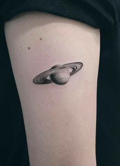 a small saturn tattoo on the arm