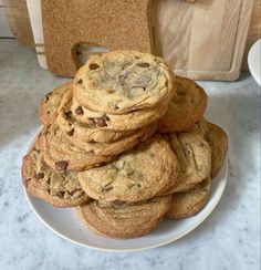 a stack of chocolate chip cookies sitting on top of a white plate