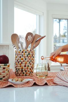 a person pouring wine into a glass with wooden spoons and utensils in it