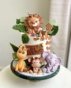 a three tiered cake decorated with animals and giraffes