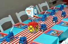 a table set up for a thomas the train birthday party with blue and red decorations