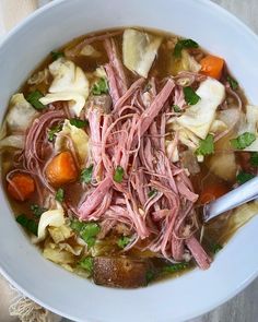 a bowl of soup with meat and vegetables in it on top of a table cloth