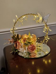 a cake decorated with flowers and butterflies on top of a wooden table next to a wall