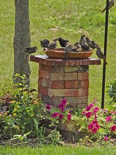 a flock of birds sitting on top of a brick fire hydrant next to flowers