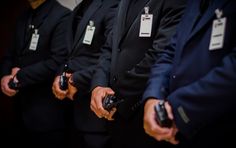 four men in suits holding their cell phones