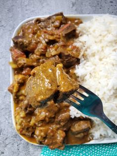 a close up of a plate of food with rice and meat on it, next to a fork