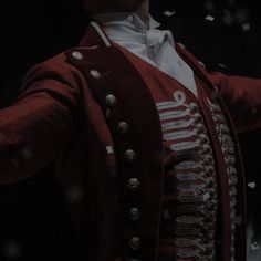 a man in a red jacket and white shirt with his hands out to the side